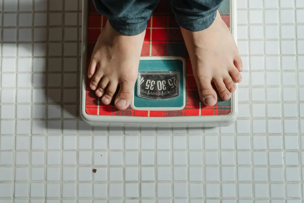 A person standing on a digital weighing scale to monitor their weight.