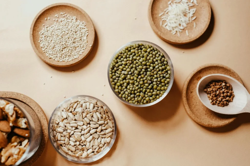 An assortment of carbohydrate-rich foods, including pasta, bread, rice, and potatoes, arranged on a wooden table.