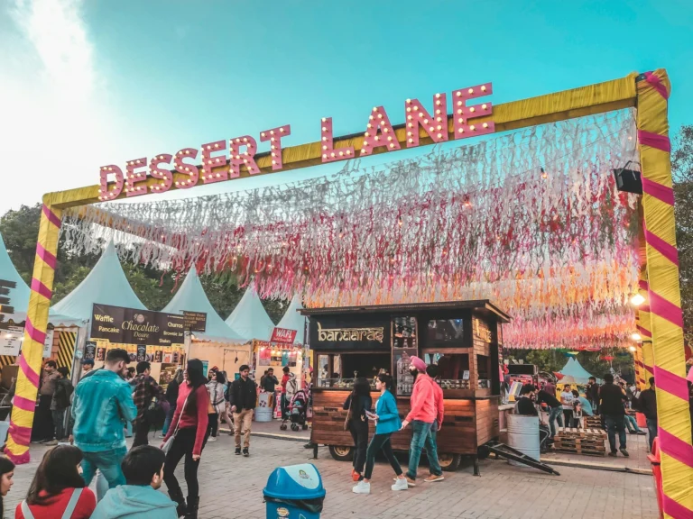 A crowded outdoor food festival with colorful tents and people enjoying various dishes.