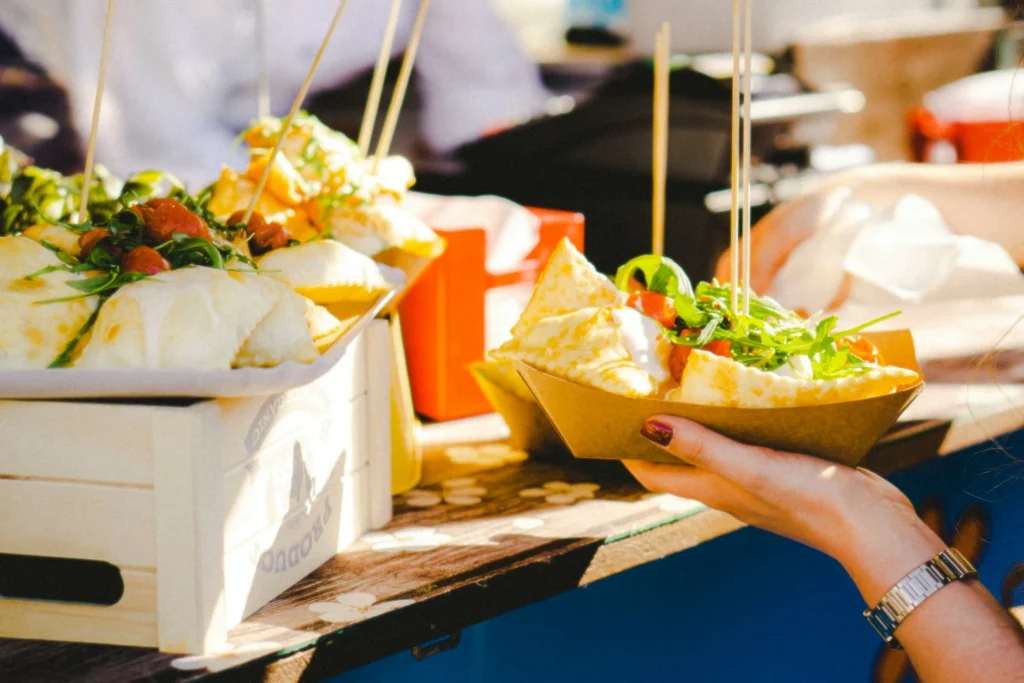 A diverse selection of food dishes displayed at a food festival, including tacos, burgers, and desserts.