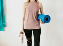 A person drinking water from a bottle during a workout session in a gym.