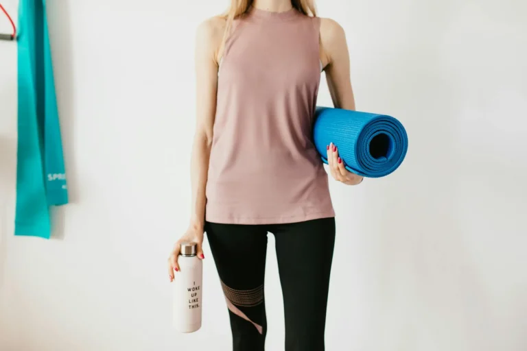 A person drinking water from a bottle during a workout session in a gym.