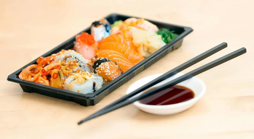 A beautifully arranged platter of sushi and sashimi with fresh fish and garnishes on a wooden board.