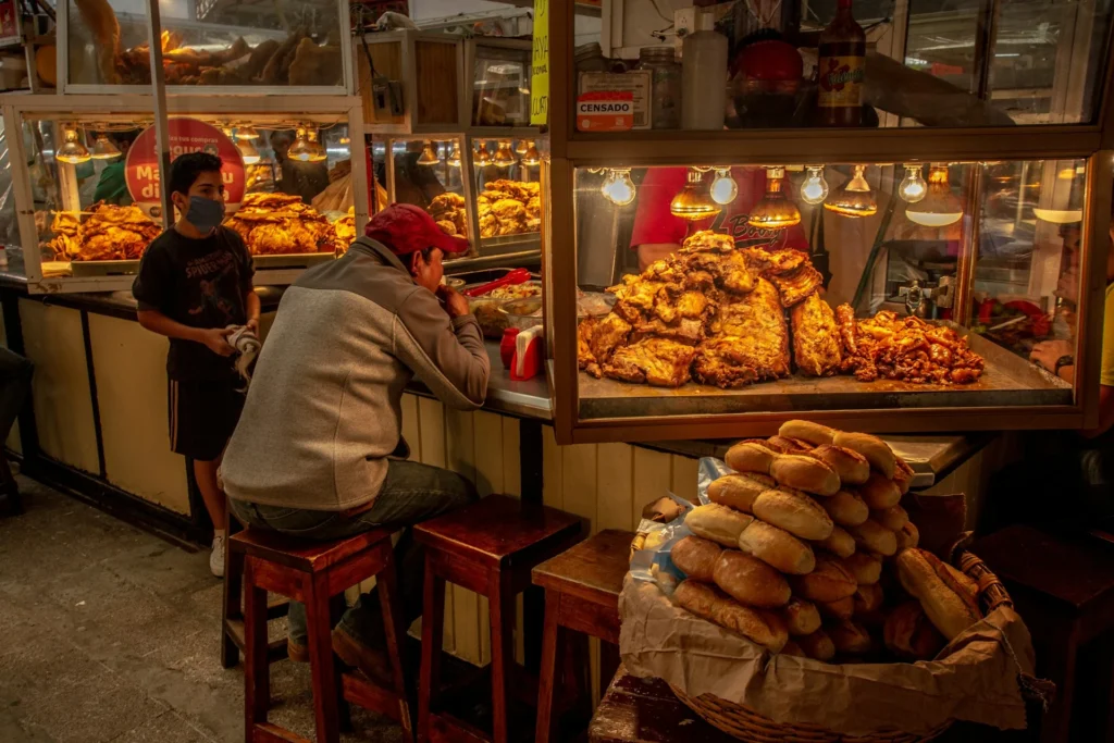 A busy Mexican street food stand with tacos, quesadillas, and other traditional dishes being prepared.