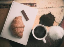 "A cup of coffee paired with a selection of pastries including croissants, macarons, and a slice of cake
