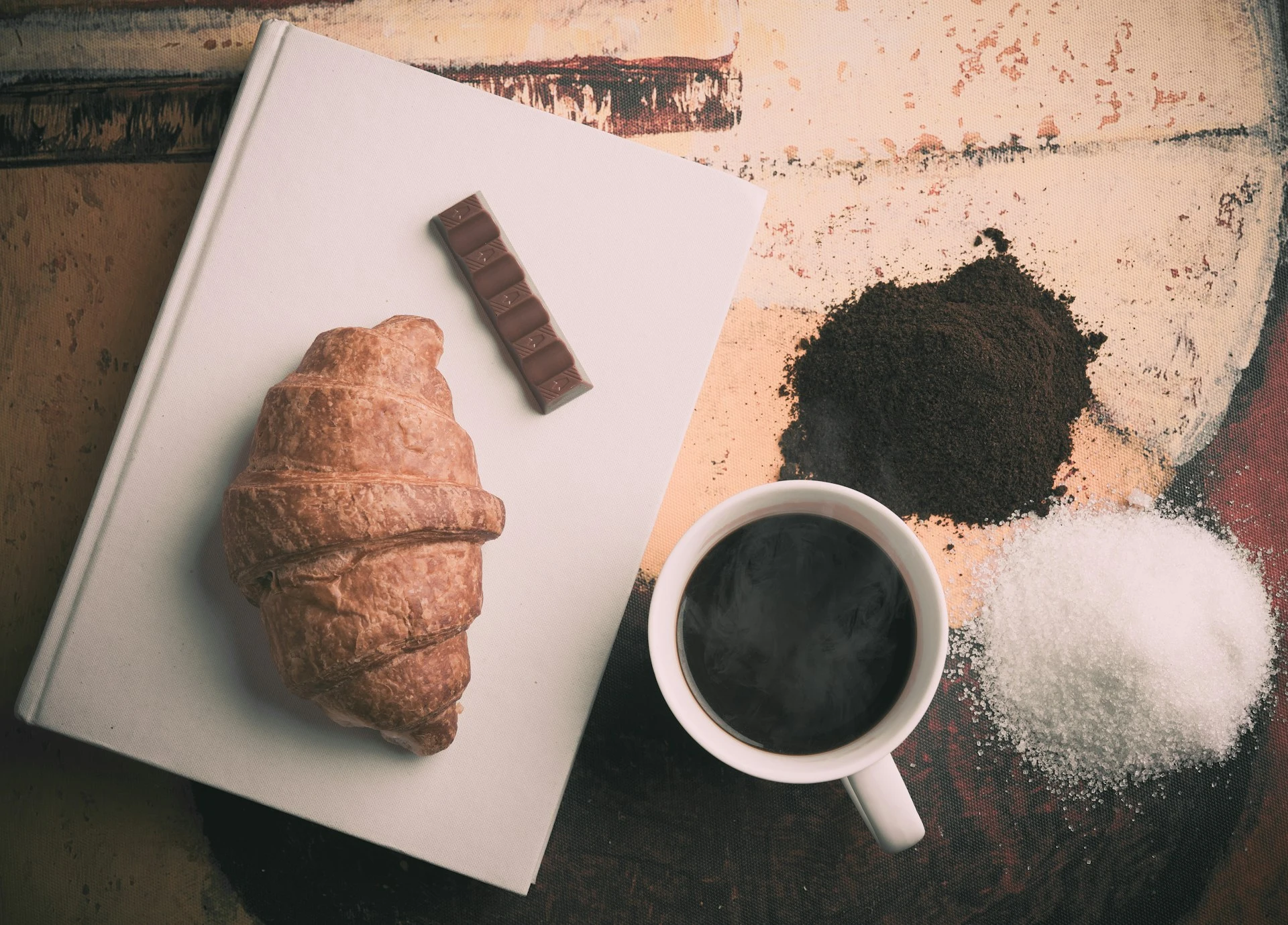 "A cup of coffee paired with a selection of pastries including croissants, macarons, and a slice of cake