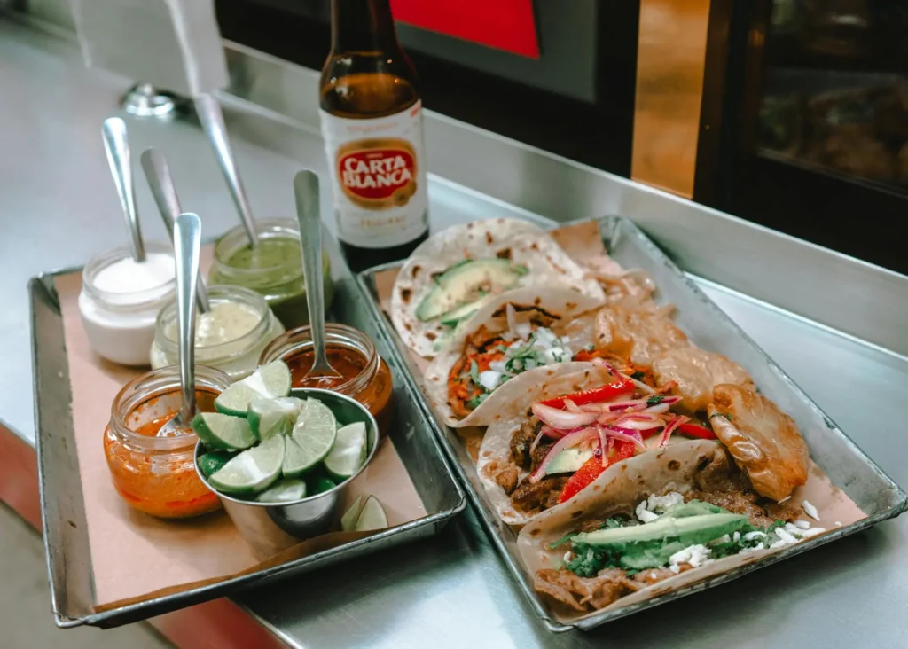 A plate of authentic Mexican tacos filled with meat, onions, and cilantro, served with lime wedges.