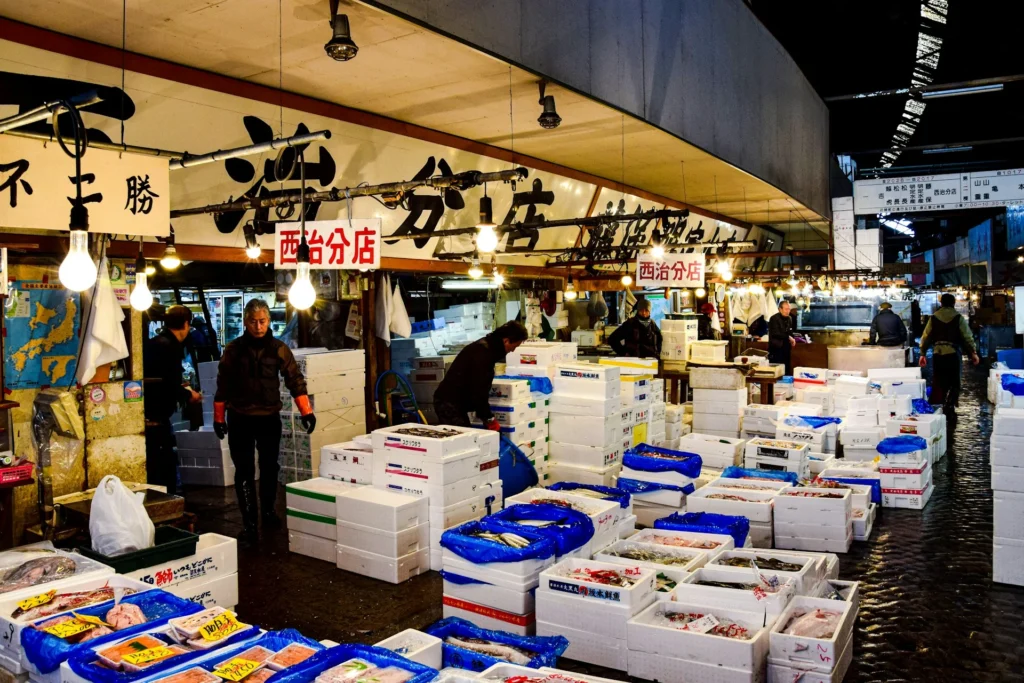 Vibrant stalls at Tsukiji Market showcasing fresh seafood, vegetables, and fruits in Tokyo.
