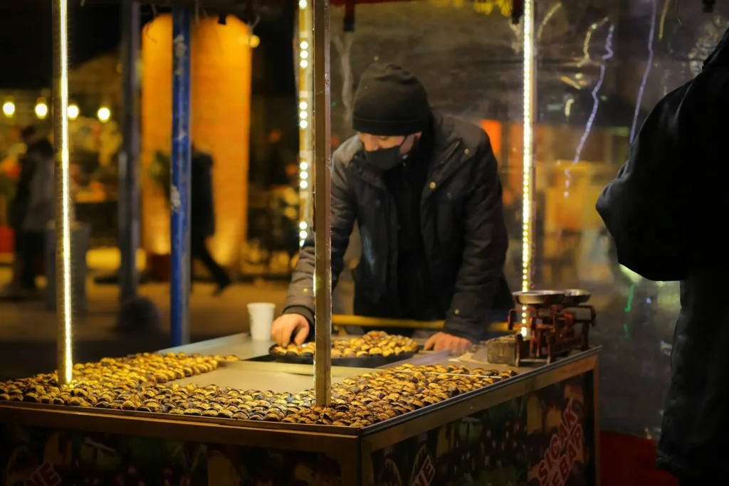 A vendor preparing Turkish street food, including kebabs and stuffed pastries, at a busy street market.