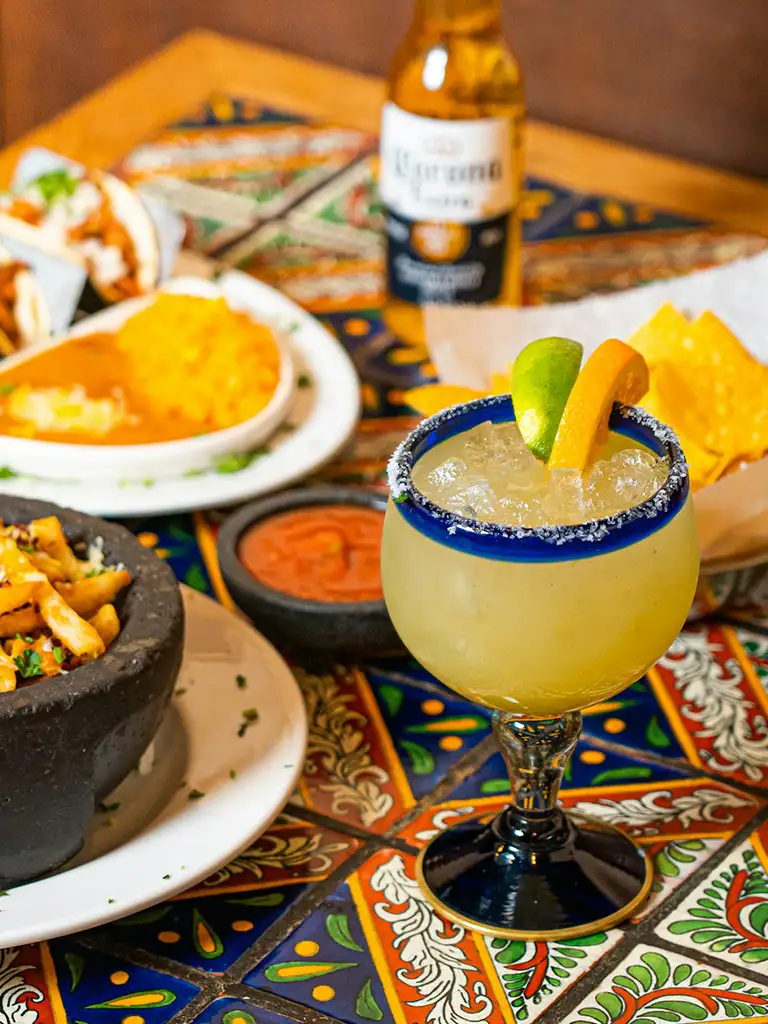 A colorful Mexican food spread with tacos, guacamole, and salsa on a wooden table.