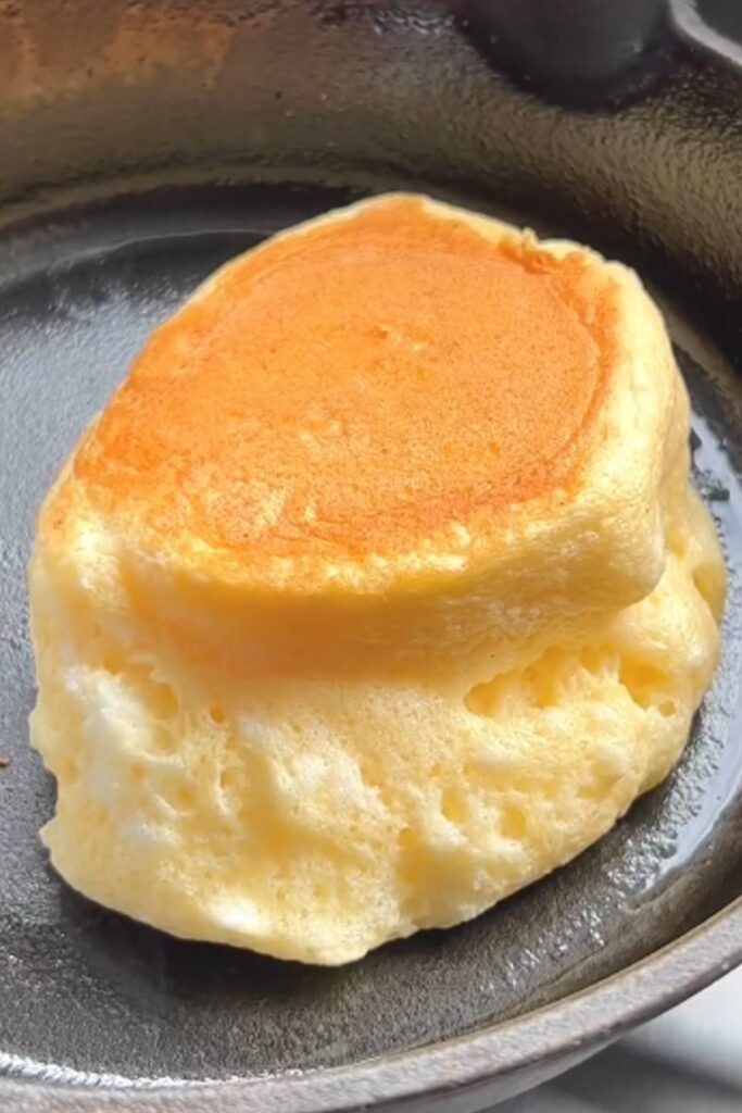 Image of golden, fluffy souffle pancakes stacked high, showcasing their light and airy texture, perfect for a delicious breakfast treat.